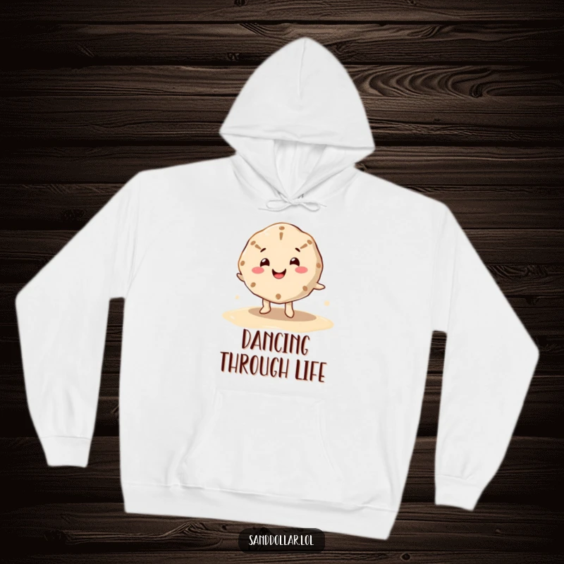 Funny hoodie featuring a happy sand dollar character, cheerful mouth, dancing on wet sand, offering warmth and beachy humor.